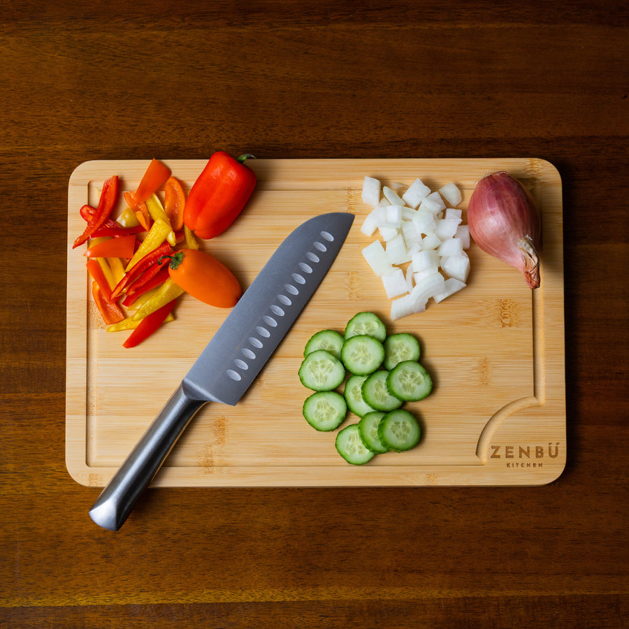 Wooden cutting board with sliced vegetables and a knife on a wooden surface
